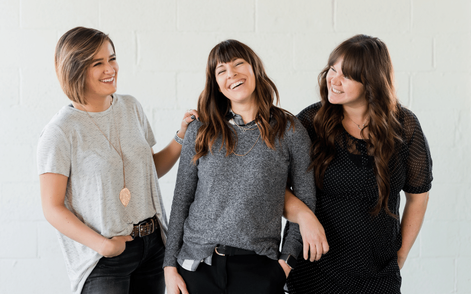 tre kvinner som ler sammen